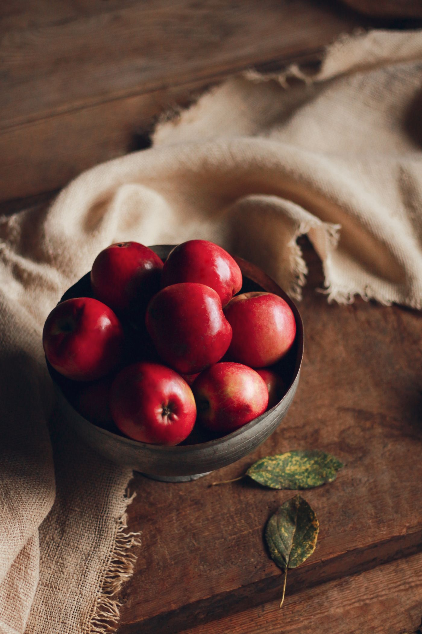 A bowl of ripe red apples on a rustic wooden table