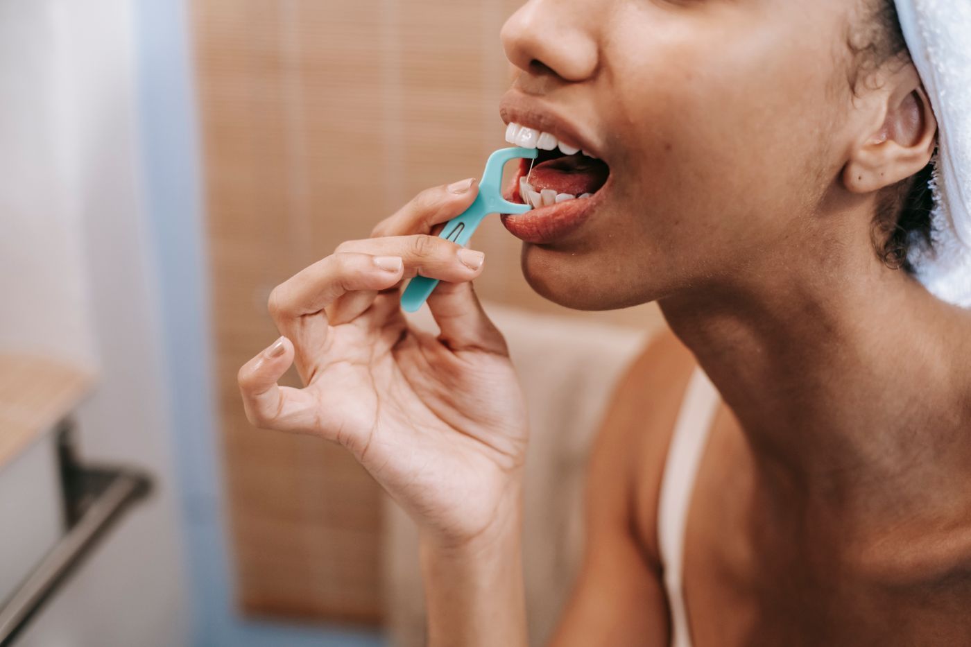 A woman cleaning between her teeth as part of a daily routine