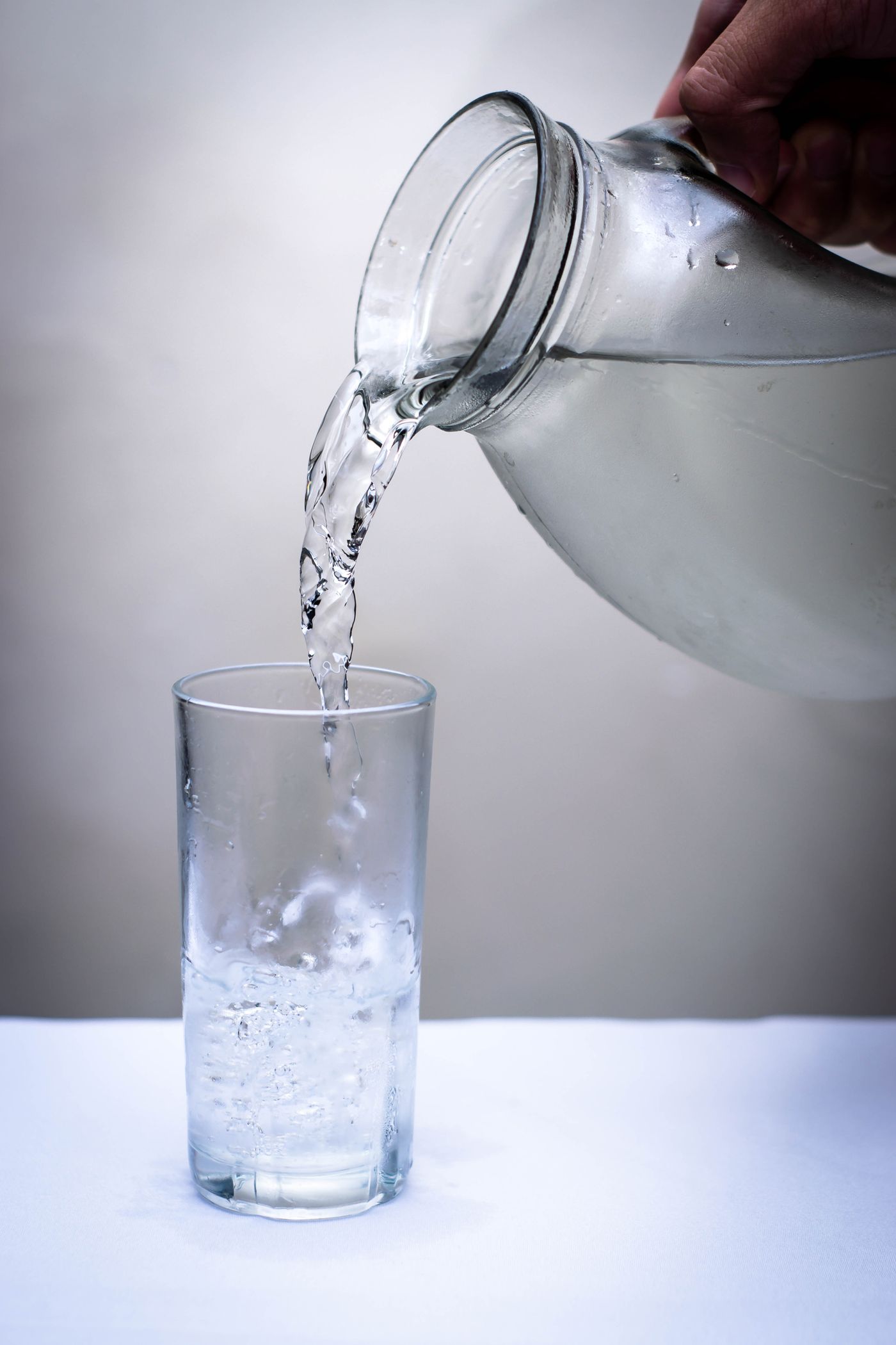 Clear water being poured from a jug into a glass